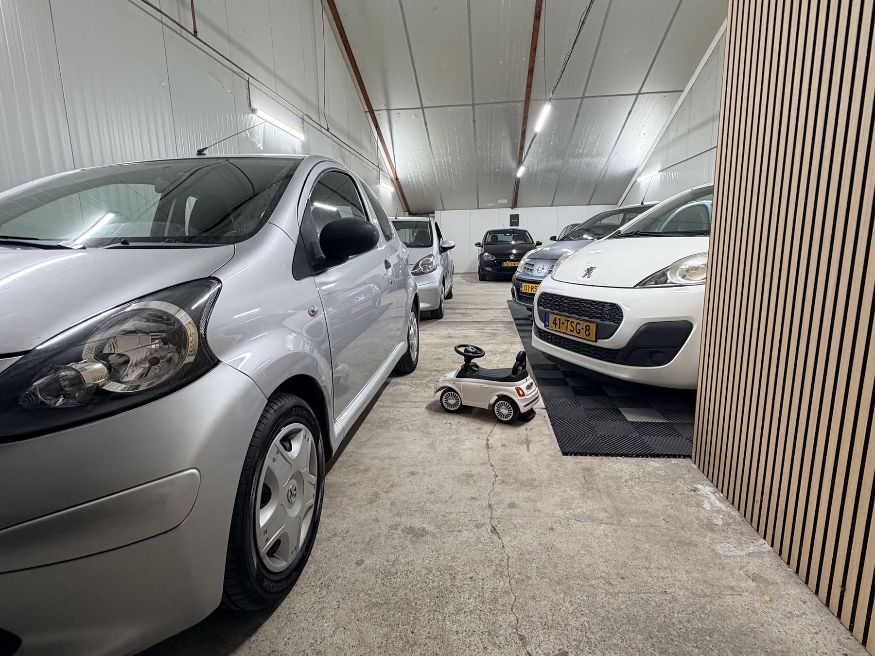 Een rij stadsauto’s langs de wand van eiken latten