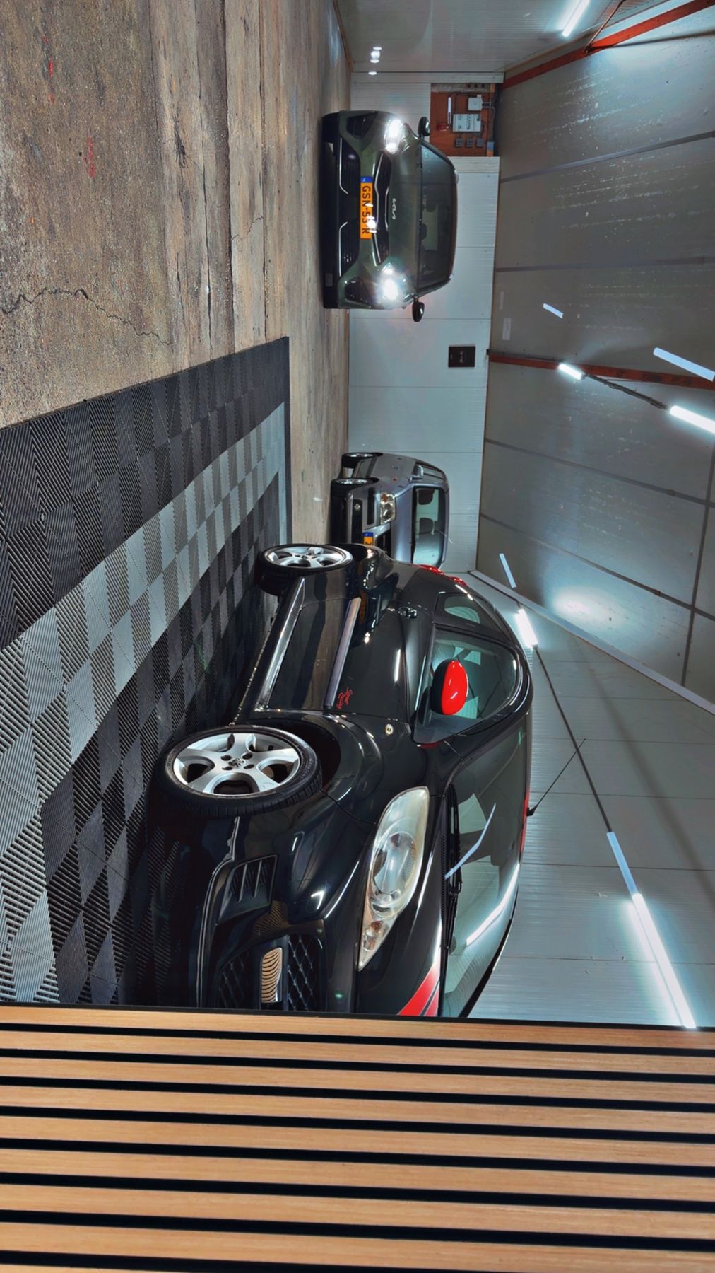Zwarte Renault Twingo op de geblokte vloer van de showroom, van bovenaf gezien