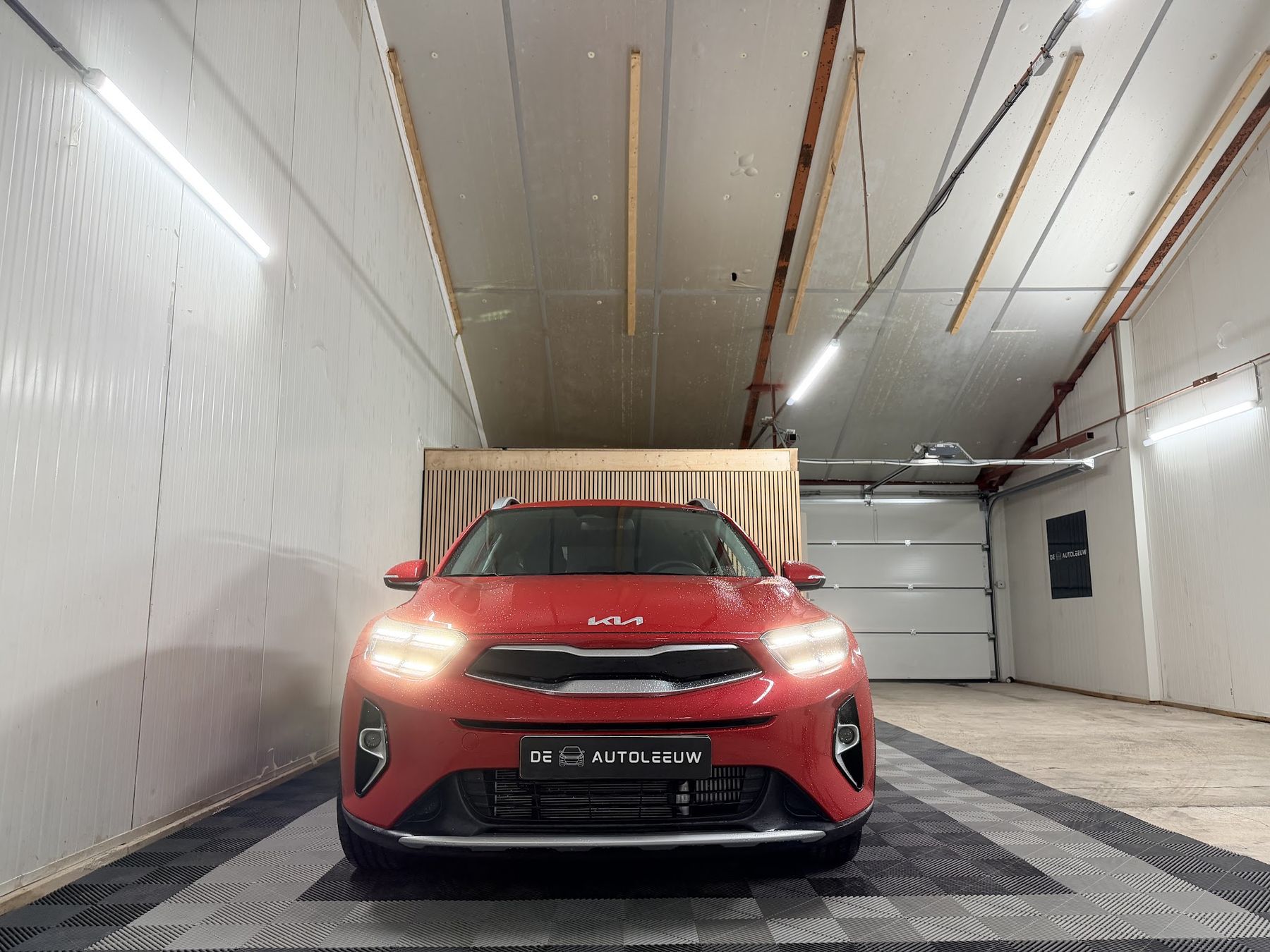 Rode Kia Stonic van voren met de lampen aan, in de showroom